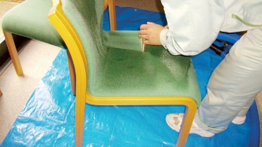 椅子の座面の汚れを落としているスタッフ