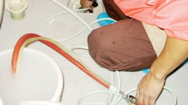 配管にホースを入れて洗浄するようす