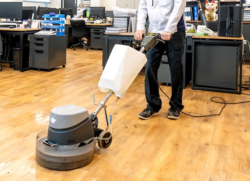 オフィスの床を洗浄機で清掃するスタッフ