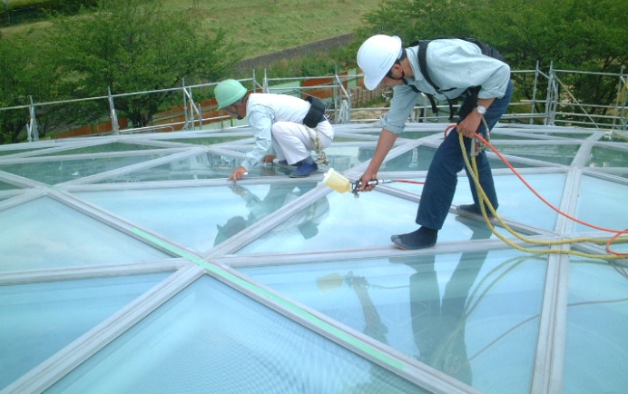 建物のガラス面に光触媒コーティング「サンライト」を施している2名のスタッフ