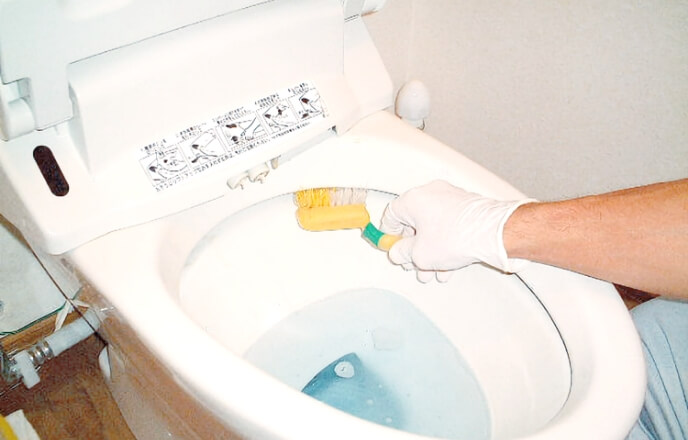 トイレ清掃の専用器具を使いトイレ清掃をするスタッフ