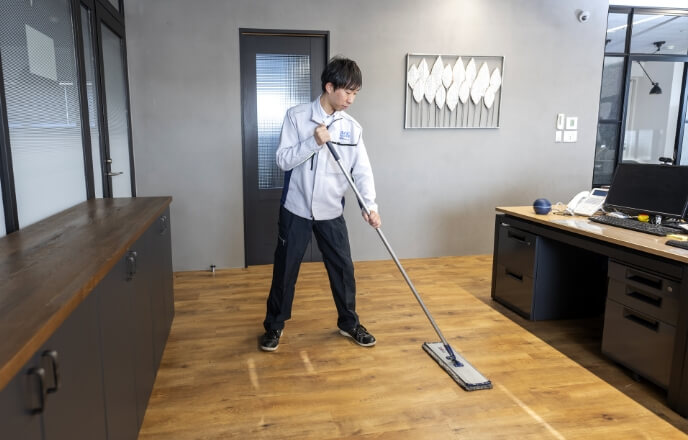 モップを使ってオフィスの定期清掃を行うスタッフ