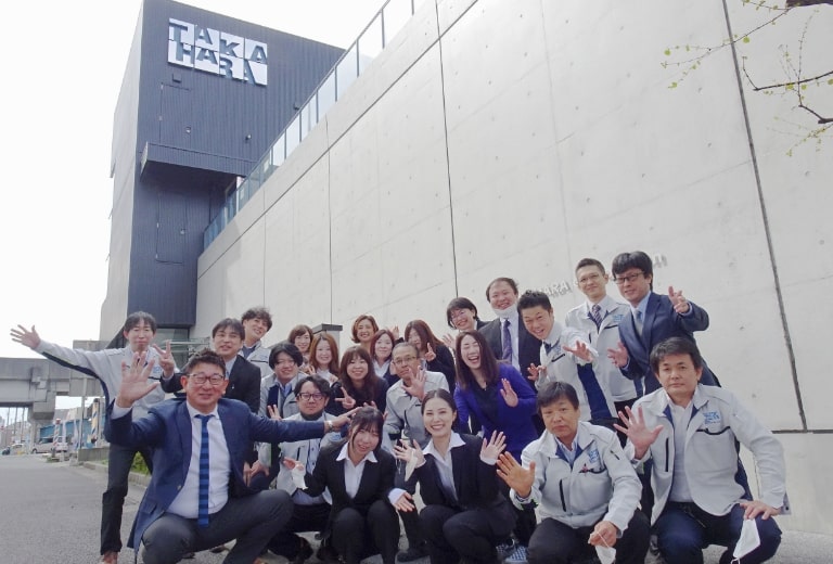 会社の前で社員たちが集合しているイメージ